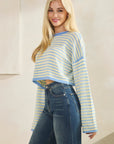 Close-up of model wearing BTTRMMT Blue Rumi Pop Stripe Knit, pastel blue and yellow cropped sweater with wide sleeves.