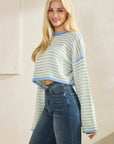 Close-up of model wearing BTTRMMT Blue Rumi Pop Stripe Knit, pastel blue and yellow cropped sweater with wide sleeves.
