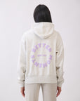 Model wearing BTTRMMT gray hoodie with lilac “Better Moments Edit 001” logo on the back, cozy minimal streetwear look.