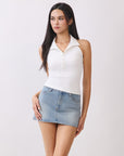 Model wearing BTTRMMT Cora Halter Top in white, a fitted sleeveless polo-style tank with button detail styled with light denim jeans.