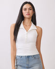 Model wearing BTTRMMT Cora Halter Top in white, a fitted sleeveless polo-style tank with button detail styled with light denim jeans.