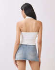 Back view of model wearing BTTRMMT Cora Halter Top in white, featuring a clean open-back halter design styled with light denim jeans.