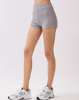 Side view of model wearing BTTRMMT Lia Ribbed Shorts in light gray, showing the fitted ribbed knit texture and high-rise waist