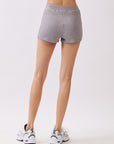 Back view of model wearing BTTRMMT Lia Ribbed Shorts in light gray, highlighting the snug fit and ribbed knit texture.
