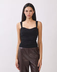 Model wearing BTTRMMT The Brielle Top, black ruched tank with wide straps and straight neckline, styled with brown faux leather pants.