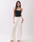 Model wearing BTTRMMT Ivory Sophia Pants with a high waist, pleated front, and wide-leg silhouette for an elegant, tailored look.