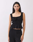 BTTRMMT black ruffle sleeveless top with tie detail, styled with black pants for a chic everyday look