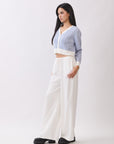 Side view of model wearing BTTRMMT Ivory Calia Pants with a relaxed wide-leg fit, paired with a cropped blue and white knit cardigan.