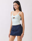 Back view of model wearing BTTRMMT mint cutout tank top with scoop neckline and dark denim mini skirt.