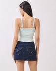 Back view of model wearing BTTRMMT mint cutout tank top with straps, paired with dark denim mini skirt.