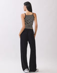 Back view of BTTRMMT Black Yuna Soft Wide Leg Pants with a drawstring waist and relaxed fit, styled with a striped knit tank and sneakers.