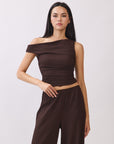 Model wearing the BTTRMMT Daniela Off-Duty Set in brown, featuring a one-shoulder ruched top and matching wide-leg pants for an elevated casual look.