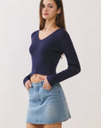 Model side view wearing BTTRMMT Alina Vneck Sweater in navy, fitted ribbed knit silhouette, styled with denim skirt.