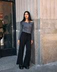Model wearing the BTTRMMT Camille Zip Knit in charcoal gray with black wide-leg pants, styled outdoors against a concrete building.