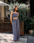 Model wearing BTTRMMT Denim Olivyn Set in blue with a cropped square-neck top and wide-leg pants while standing outside a cafรฉ.