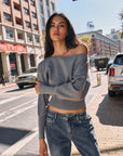 Model in BTTRMMT Gray Tessa Boatneck Sweater, off-shoulder knit styled with jeans in sunlight.