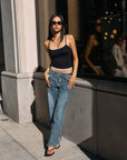 Model wearing BTTRMMT Drop Zone Low Rise Wide Leg Jeans in vintage blue, styled with a gray knit top while standing on a city street.