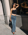 Model wearing BTTRMMT Drop Zone Low Rise Wide Leg Jeans in vintage blue, styled with a gray knit top while standing on a city street.