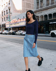 Model wearing BTTRMMT Fiona Denim Midi Skirt with front pockets and a straight mid-length fit, styled for an everyday street look.