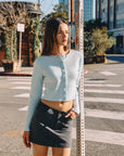 BTTRMMT Blue Sophie Ribbed Button Cardigan worn with black mini skirt, LA street style outfit, front view model standing at crosswalk.