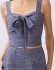 Close up of Model wearing BTTRMMT The Delilah Set, blue textured two-piece with tie-front crop top and matching wide-leg pants.