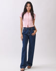 Full-body view of model wearing BTTRMMT Emery Straight Jean in dark blue denim, styled with a pink button-up knit top