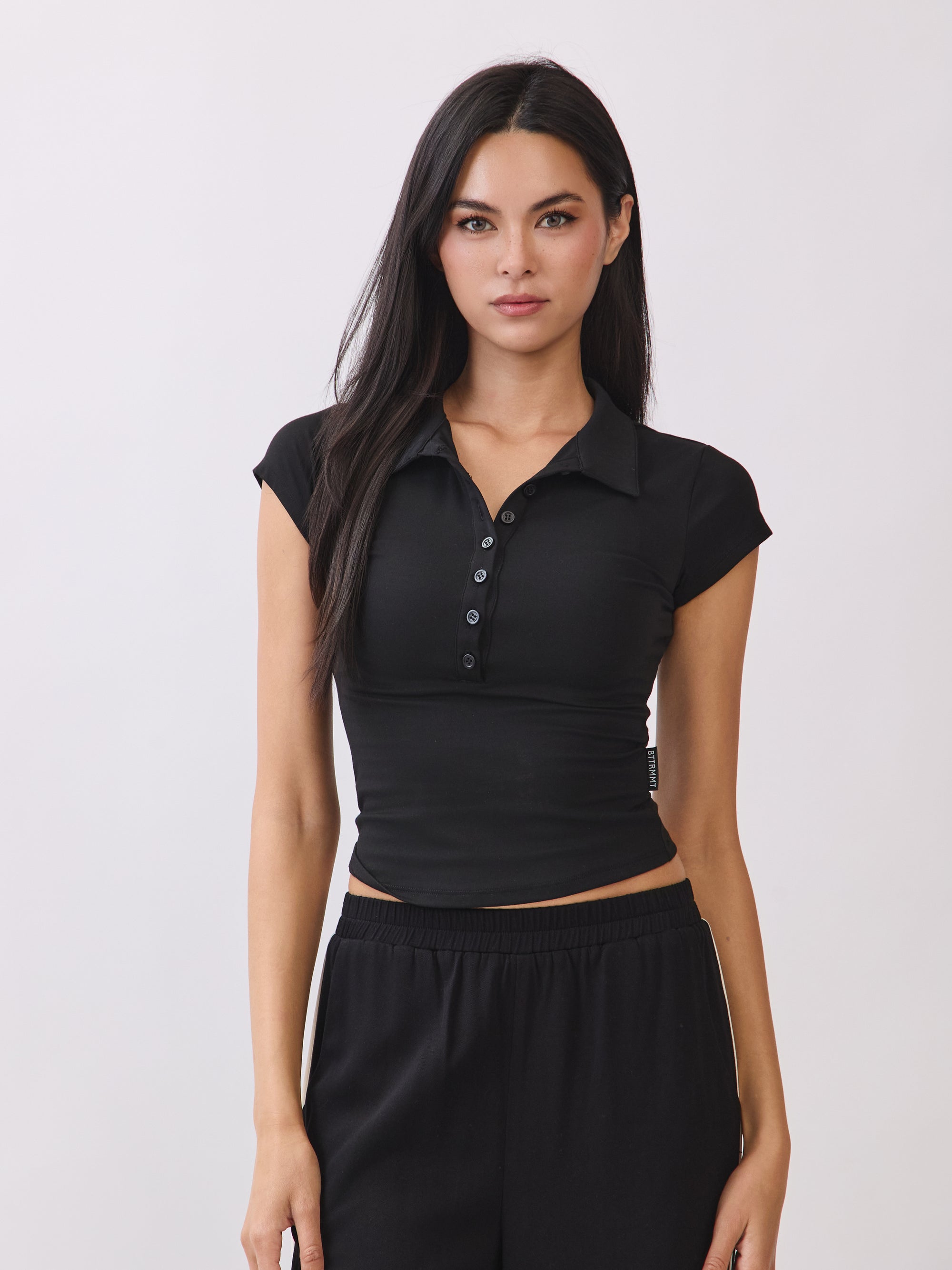 BTTRMMT Black Eliza Fitted Polo Top with a sleek, stretchy silhouette and button-front detail, styled for a clean everyday look.