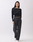 Model in BTTRMMT Black Tessa Boatneck Sweater with off-shoulder neckline and black jeans.