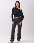 Model in BTTRMMT Black Tessa Boatneck Sweater with off-shoulder neckline and black jeans.