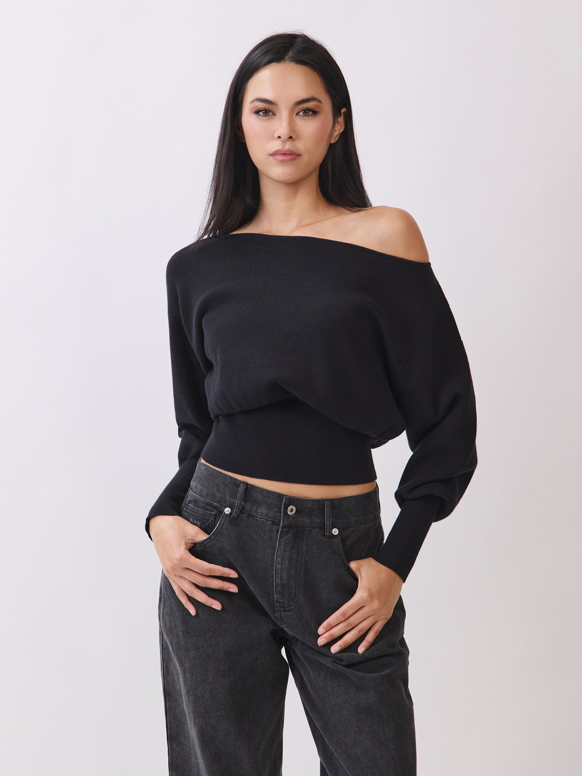 Model wearing BTTRMMT Black Tessa Boatneck Sweater, off-shoulder knit with ribbed waist.