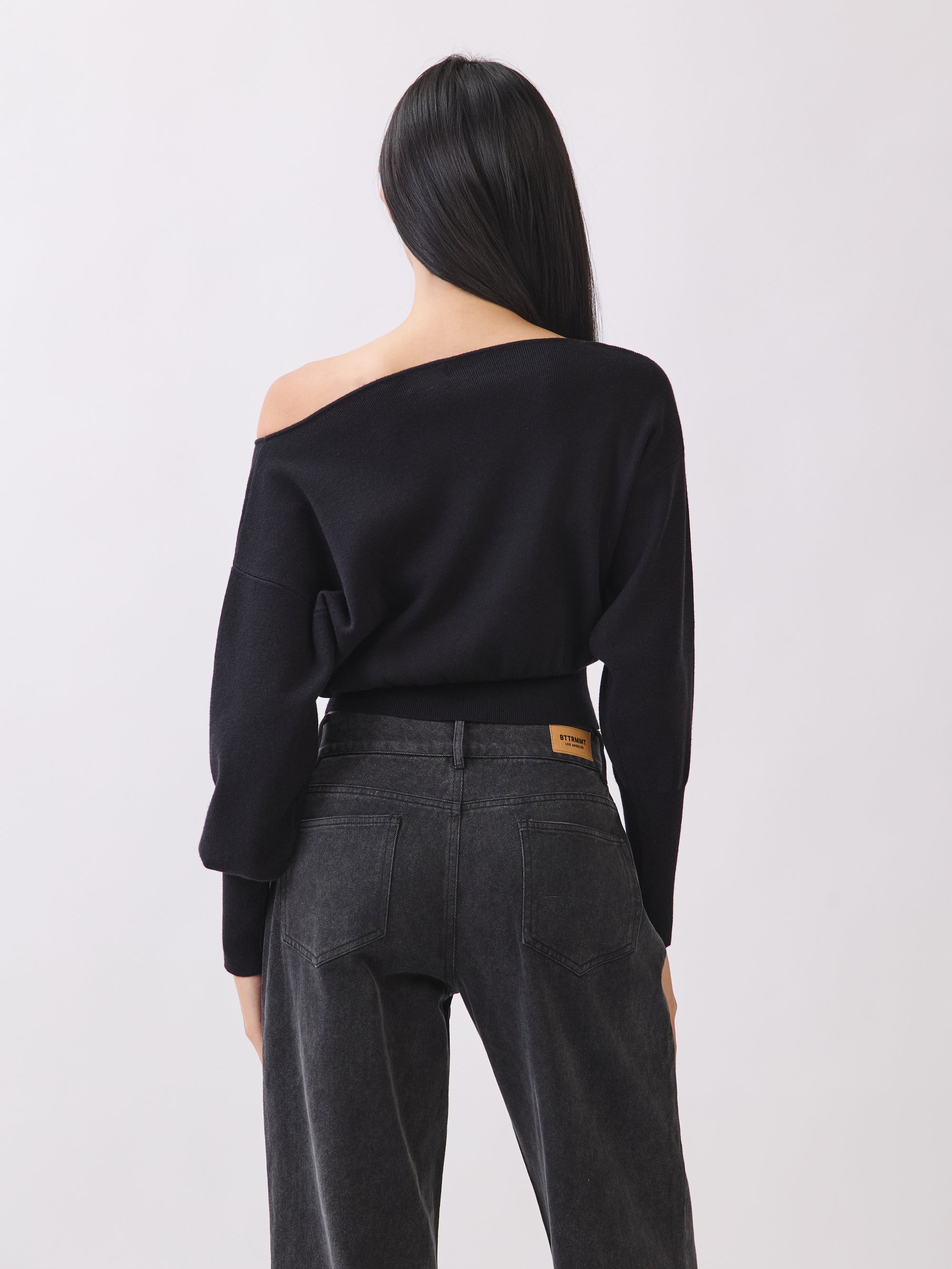 Back view of BTTRMMT Black Tessa Boatneck Sweater, relaxed off-shoulder knit with ribbed waist.
