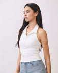 Side view of model in BTTRMMT Cora Halter Top in white, a fitted sleeveless polo-style tank paired with high-rise light denim jeans.