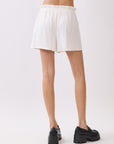 Back view of model wearing BTTRMMT Cali Paperback Shorts in ivory, showing elastic paperbag waist and relaxed rear fit.