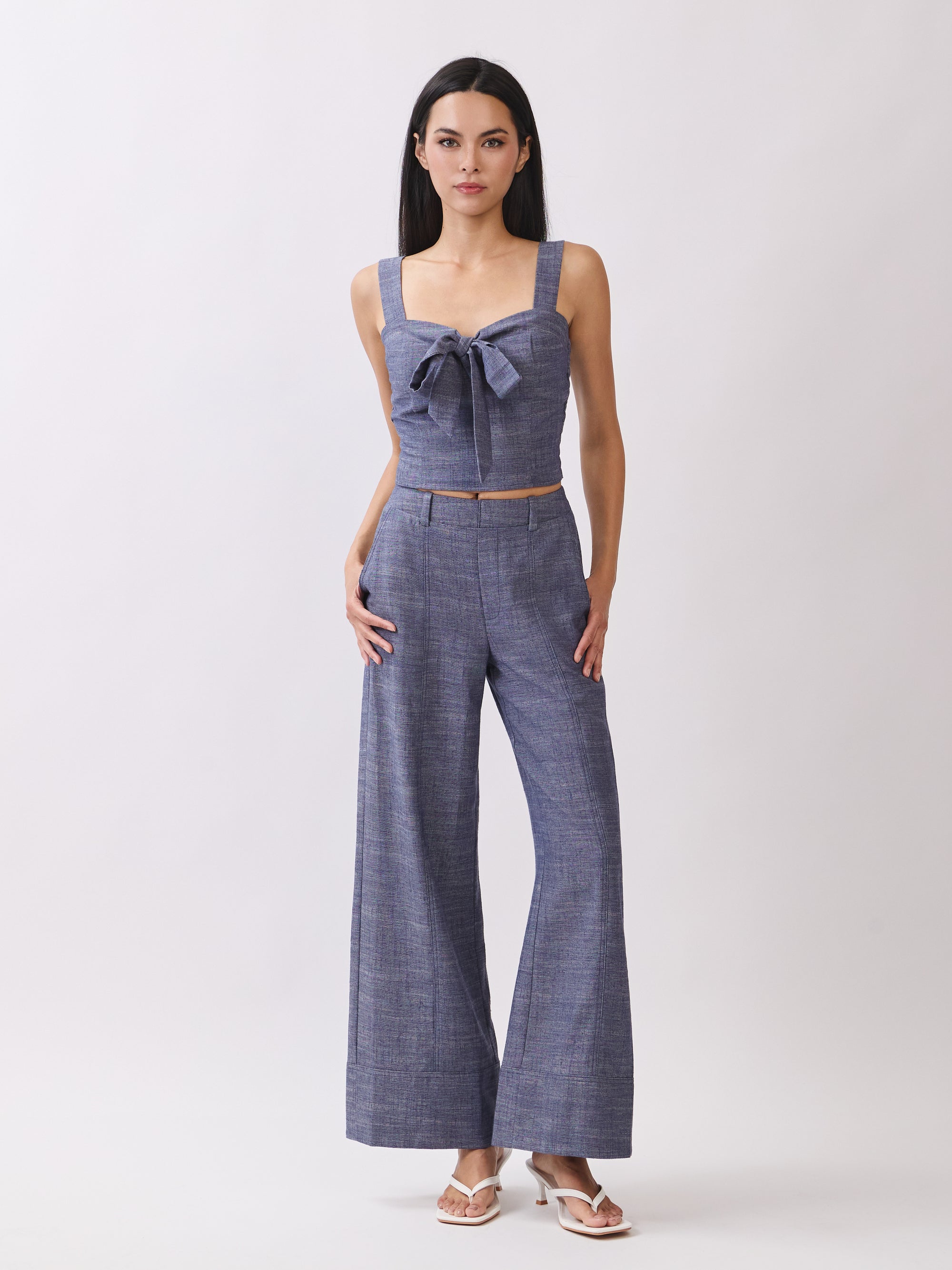 Model wearing BTTRMMT The Delilah Set, blue textured two-piece with tie-front crop top and matching wide-leg pants.