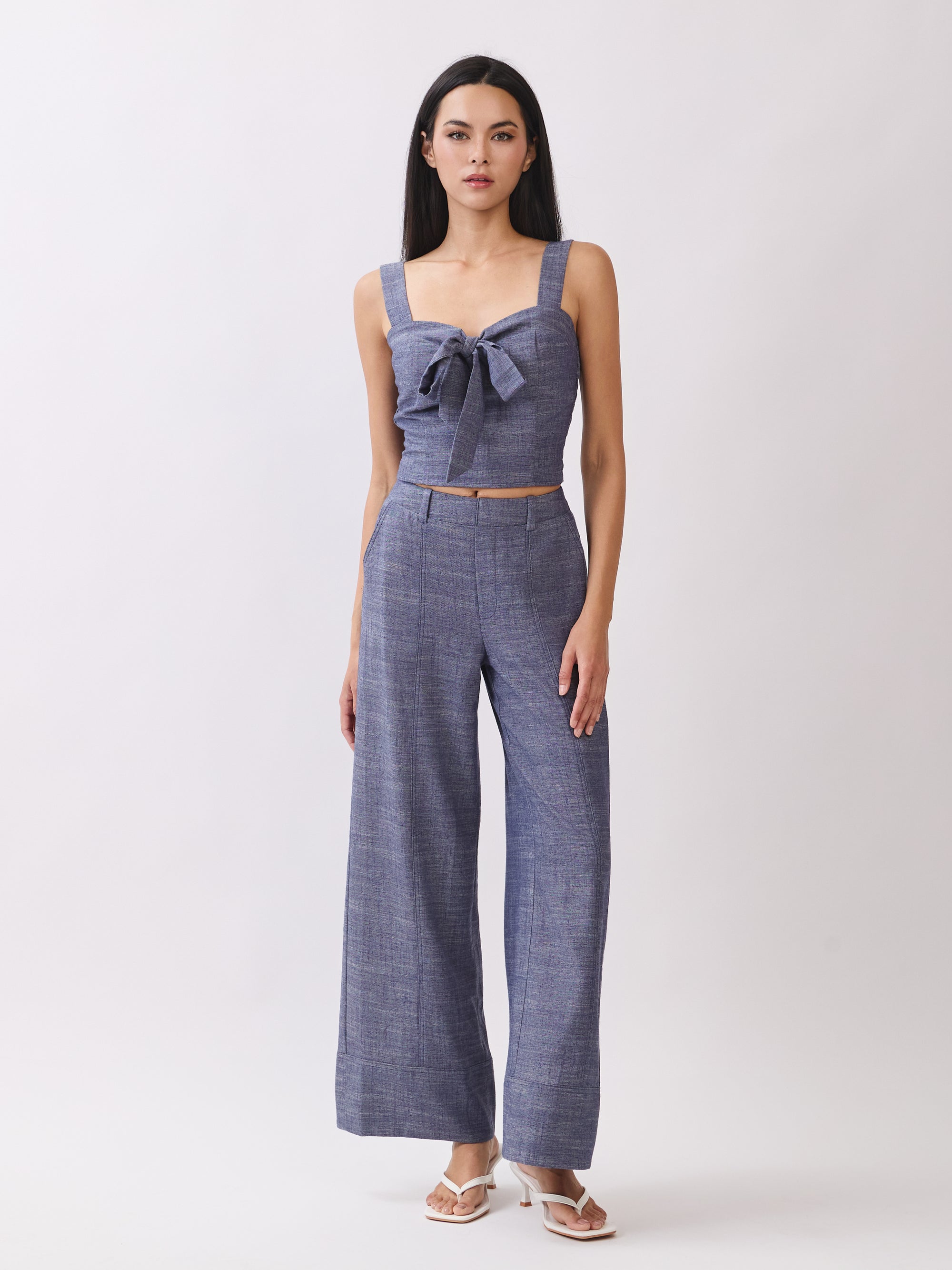 Model wearing BTTRMMT The Delilah Set, blue textured two-piece with tie-front crop top and matching wide-leg pants.
