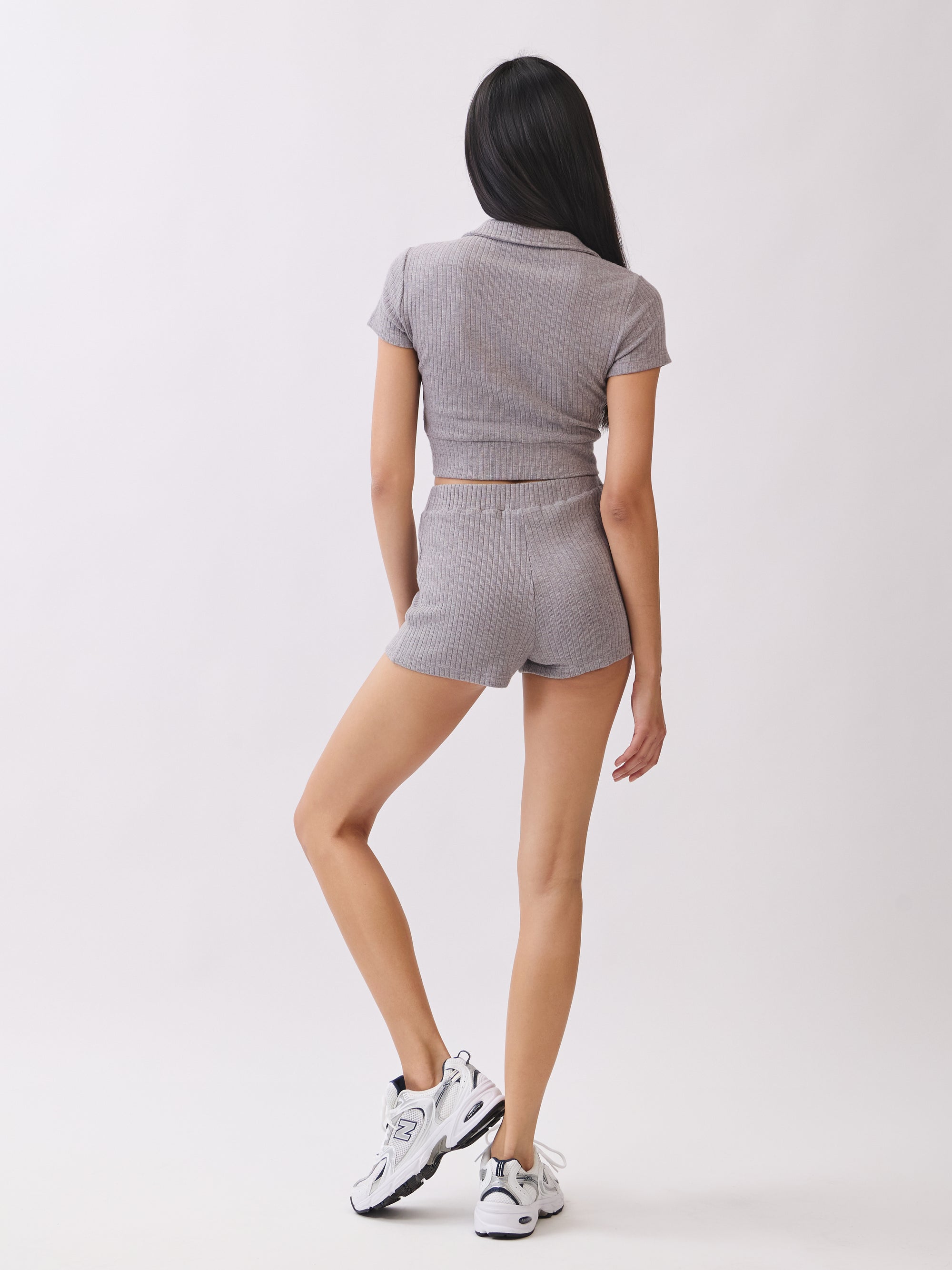 Back view of model wearing BTTRMMT Lia Ribbed Shorts in light gray with matching top, showing the fitted ribbed texture and flattering silhouette.