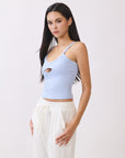 Side view of model wearing BTTRMMT light blue cutout tank top with straps and white drawstring pants.