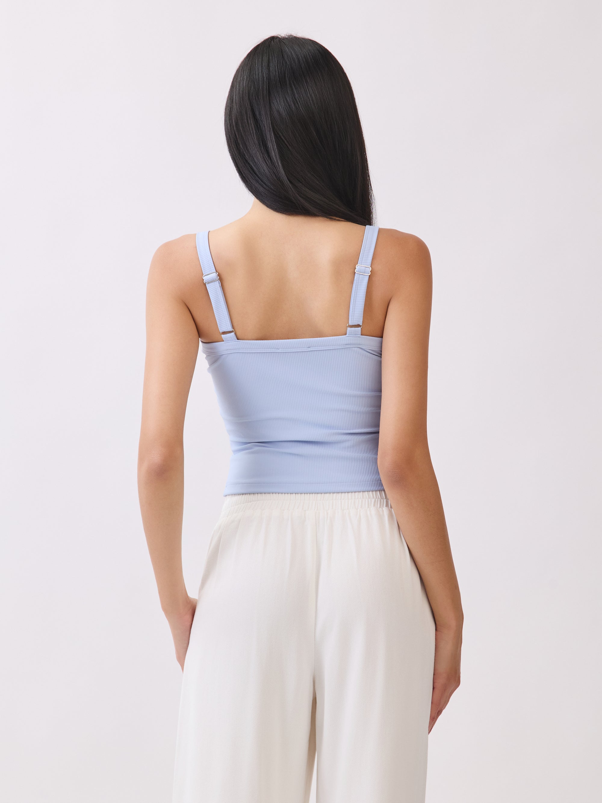 Back view of model wearing BTTRMMT light blue cutout tank top with straps, paired with white drawstring pants.
