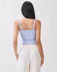 Back view of model wearing BTTRMMT light blue cutout tank top with straps, paired with white drawstring pants.