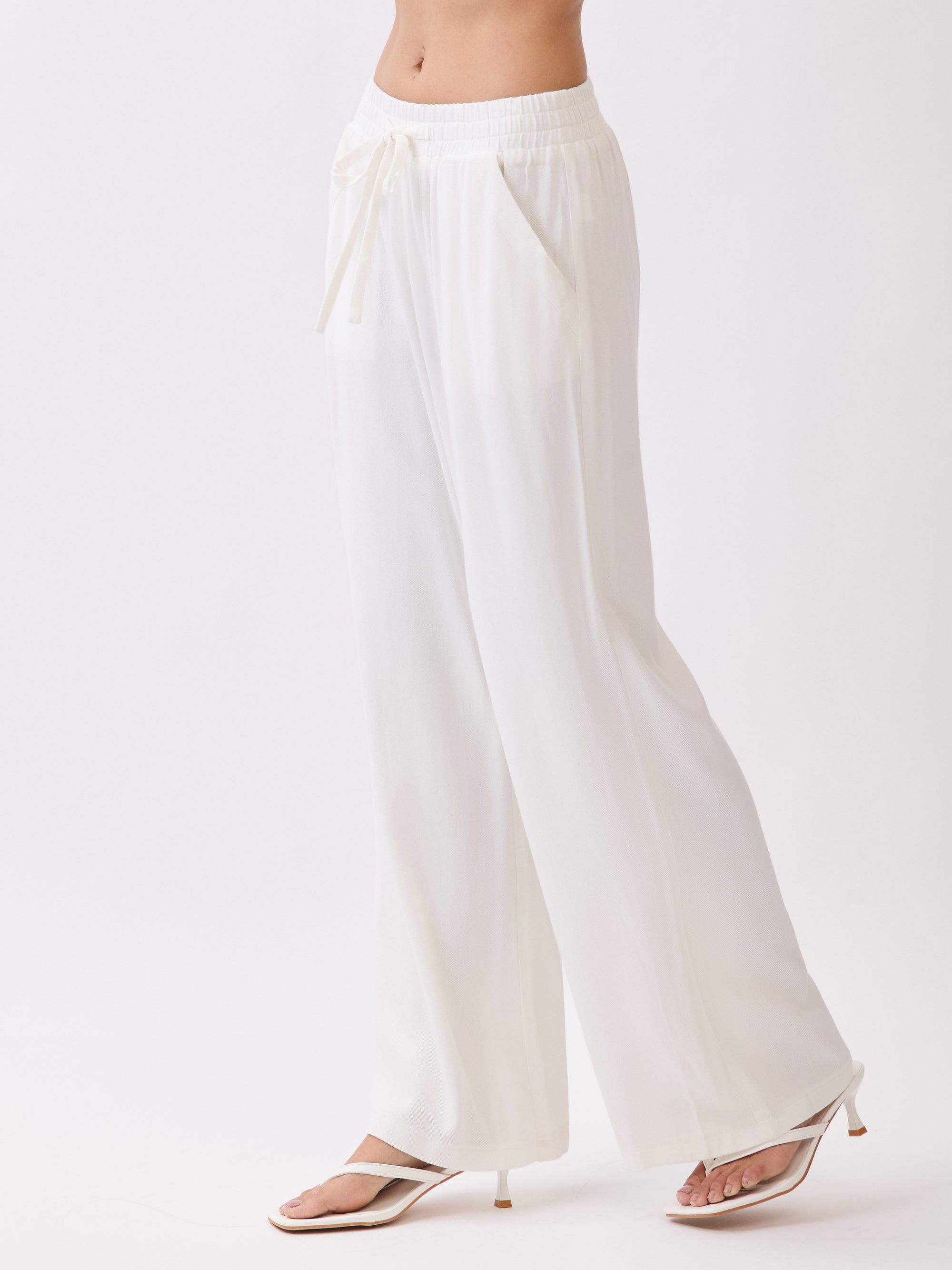 Side view of BTTRMMT Ivory Yuna Soft Wide Leg Pants featuring a flowy drape, elastic waistband, and relaxed lightweight fit.