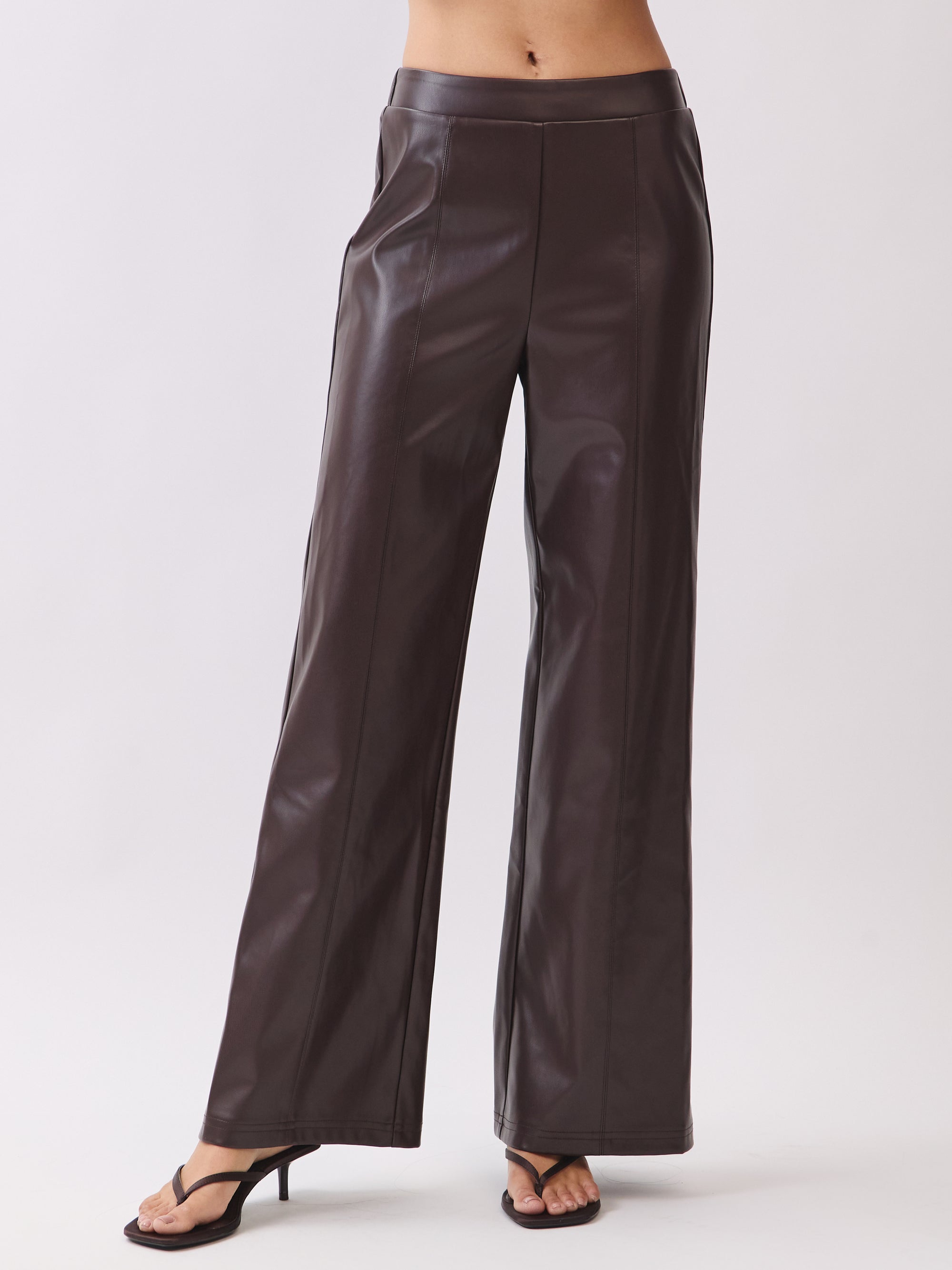Model wearing BTTRMMT dark brown faux leather pants with straight-leg fit and stitched seam detail.
