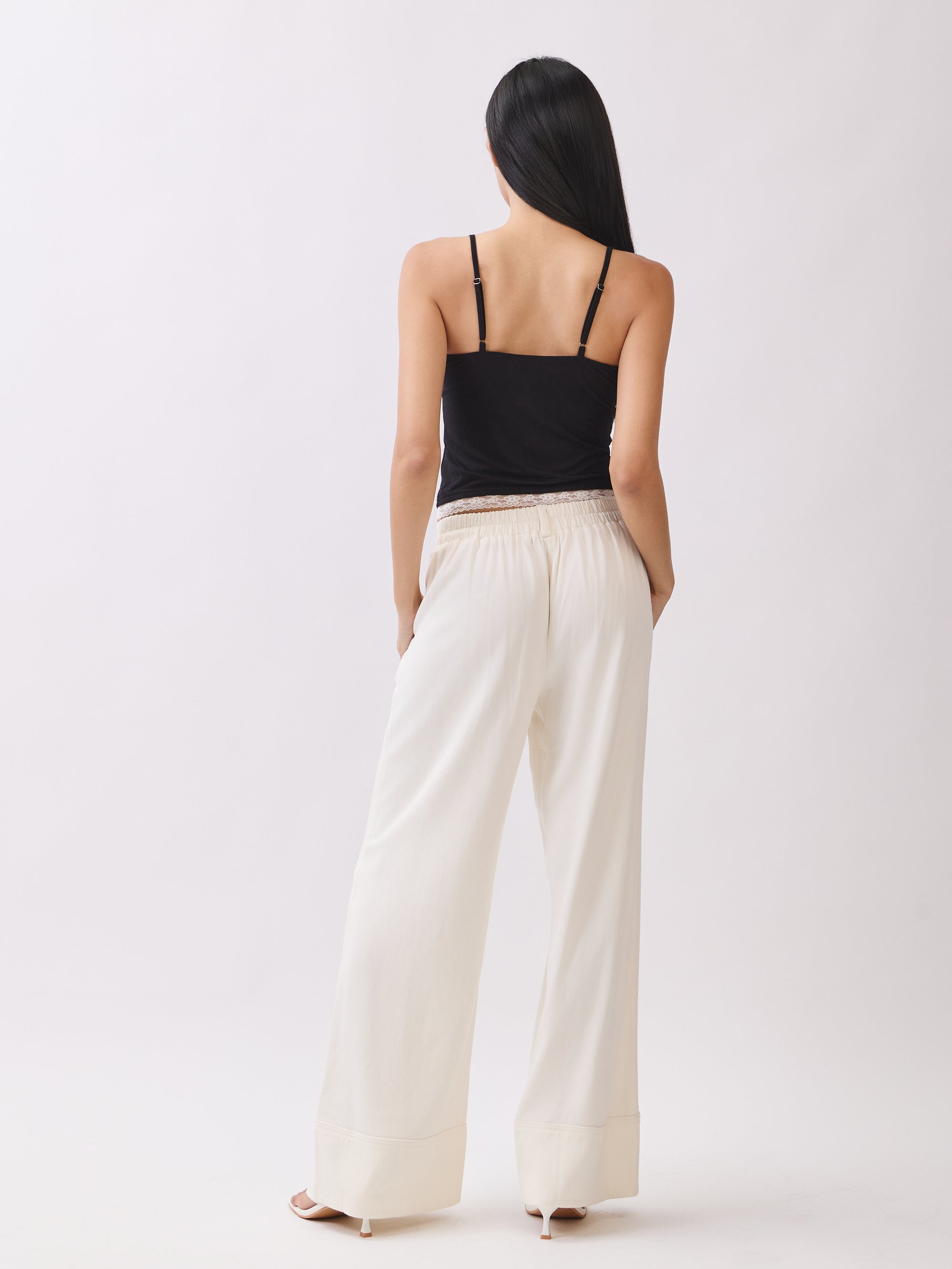 Model wearing BTTRMMT Ivory Sophia Pants with a high waist, pleated front, and wide-leg silhouette for an elegant, tailored look.