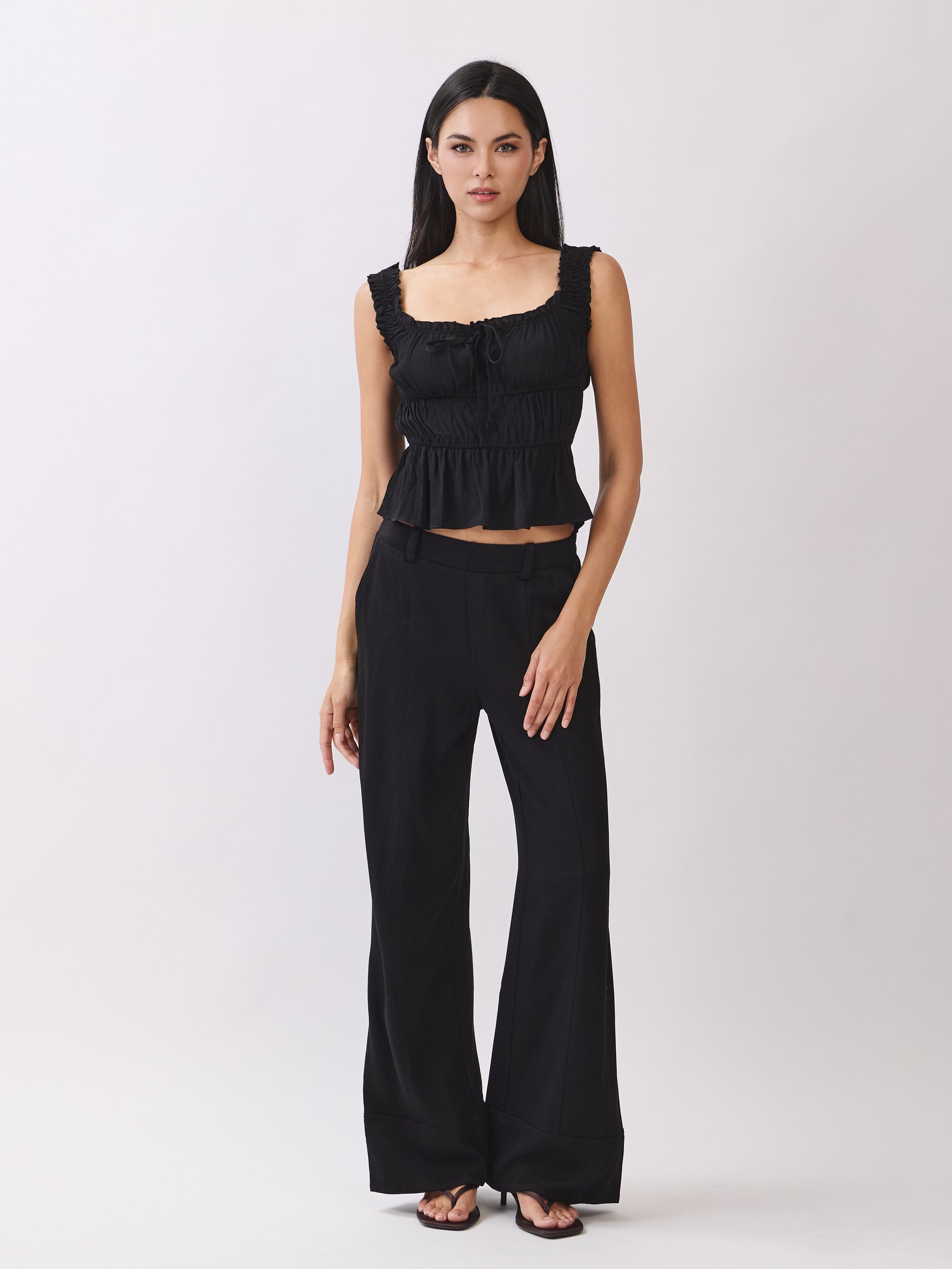 BTTRMMT black ruffle tank top paired with black wide-leg pants, showing a clean full-body minimal outfit look