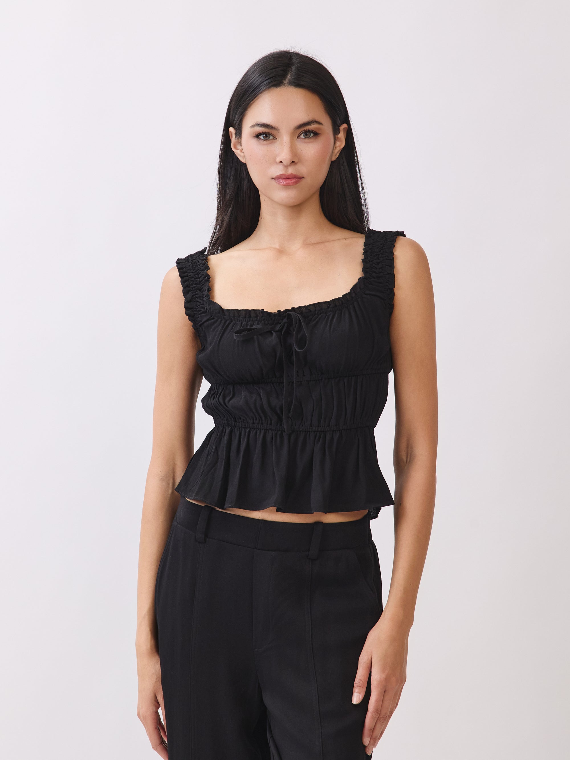BTTRMMT black ruffle sleeveless top with tie detail, styled with black pants for a chic everyday look