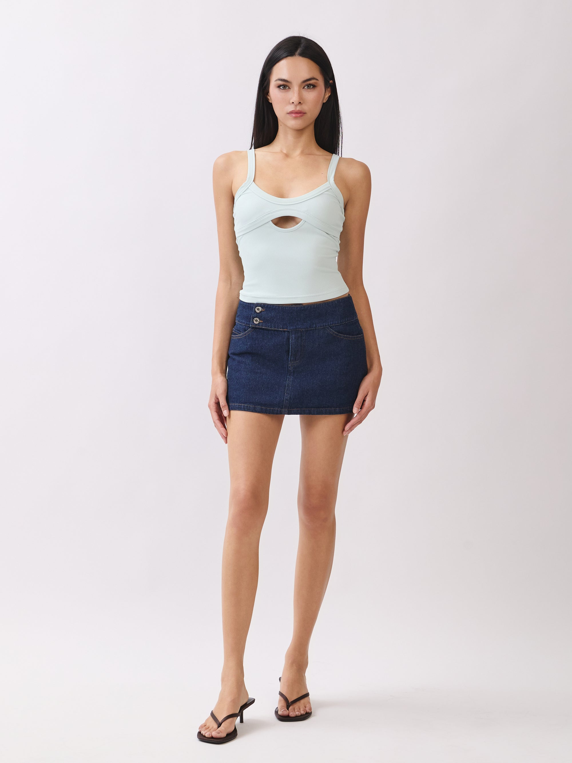 Model wearing BTTRMMT mint cutout tank top with scoop neckline, paired with dark denim mini skirt and heels.