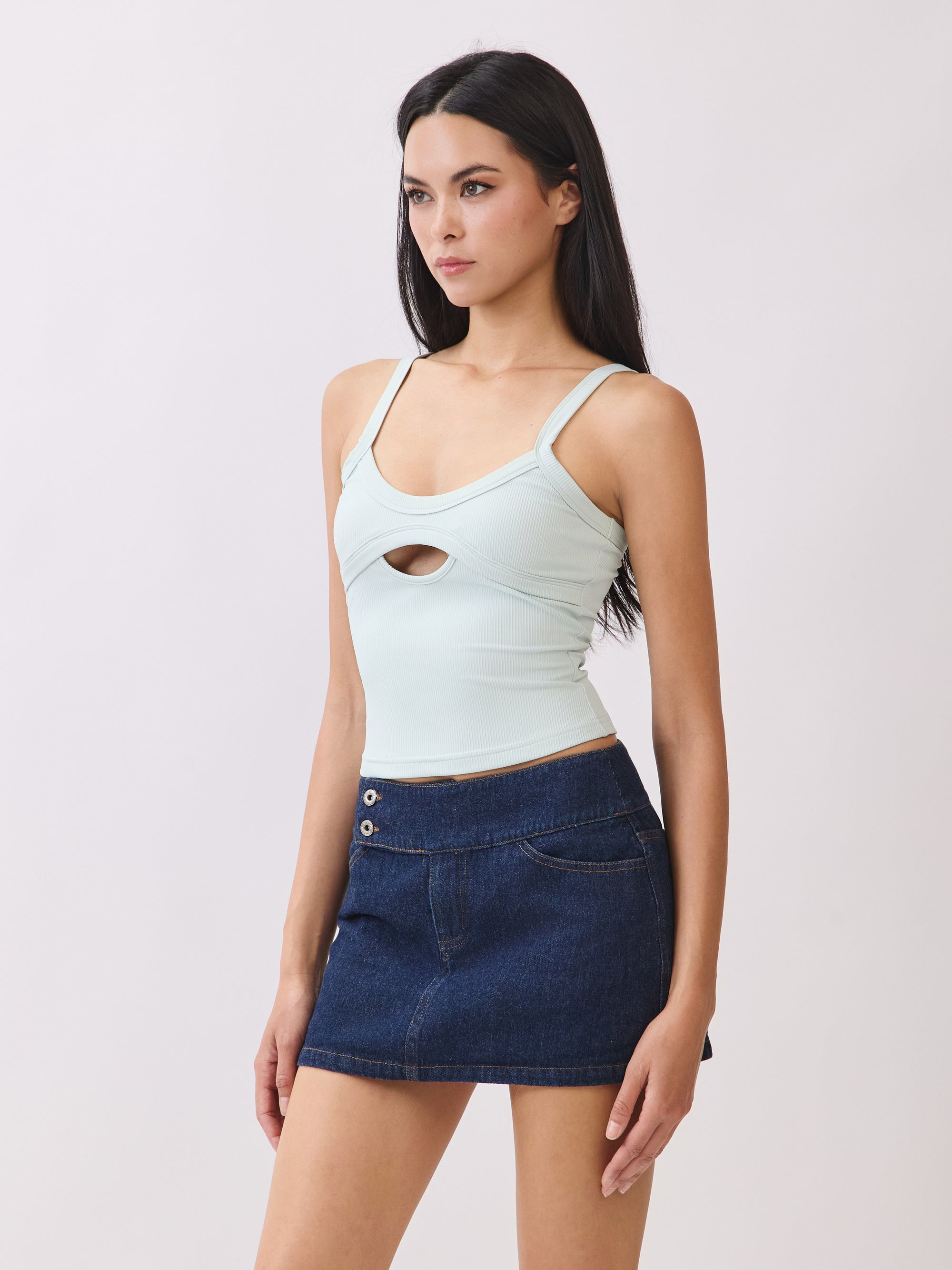 Back view of model wearing BTTRMMT mint cutout tank top with scoop neckline and dark denim mini skirt.
