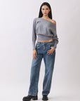 Model in BTTRMMT Gray Tessa Boatneck Sweater, off-shoulder knit with jeans and black boots.
