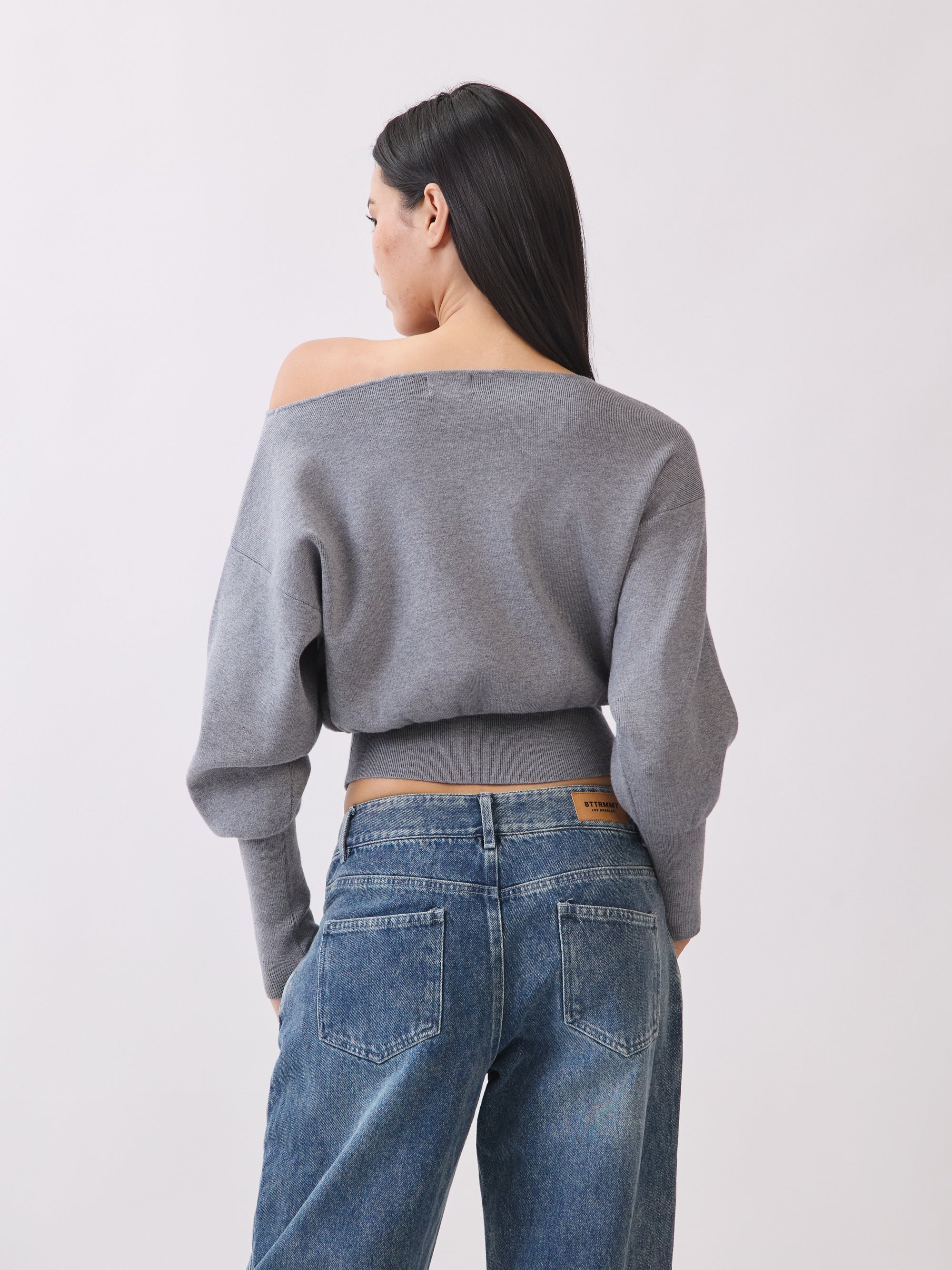 Back view of Model wearing BTTRMMT Gray Tessa Boatneck Sweater, ribbed off-shoulder knit with long sleeves.