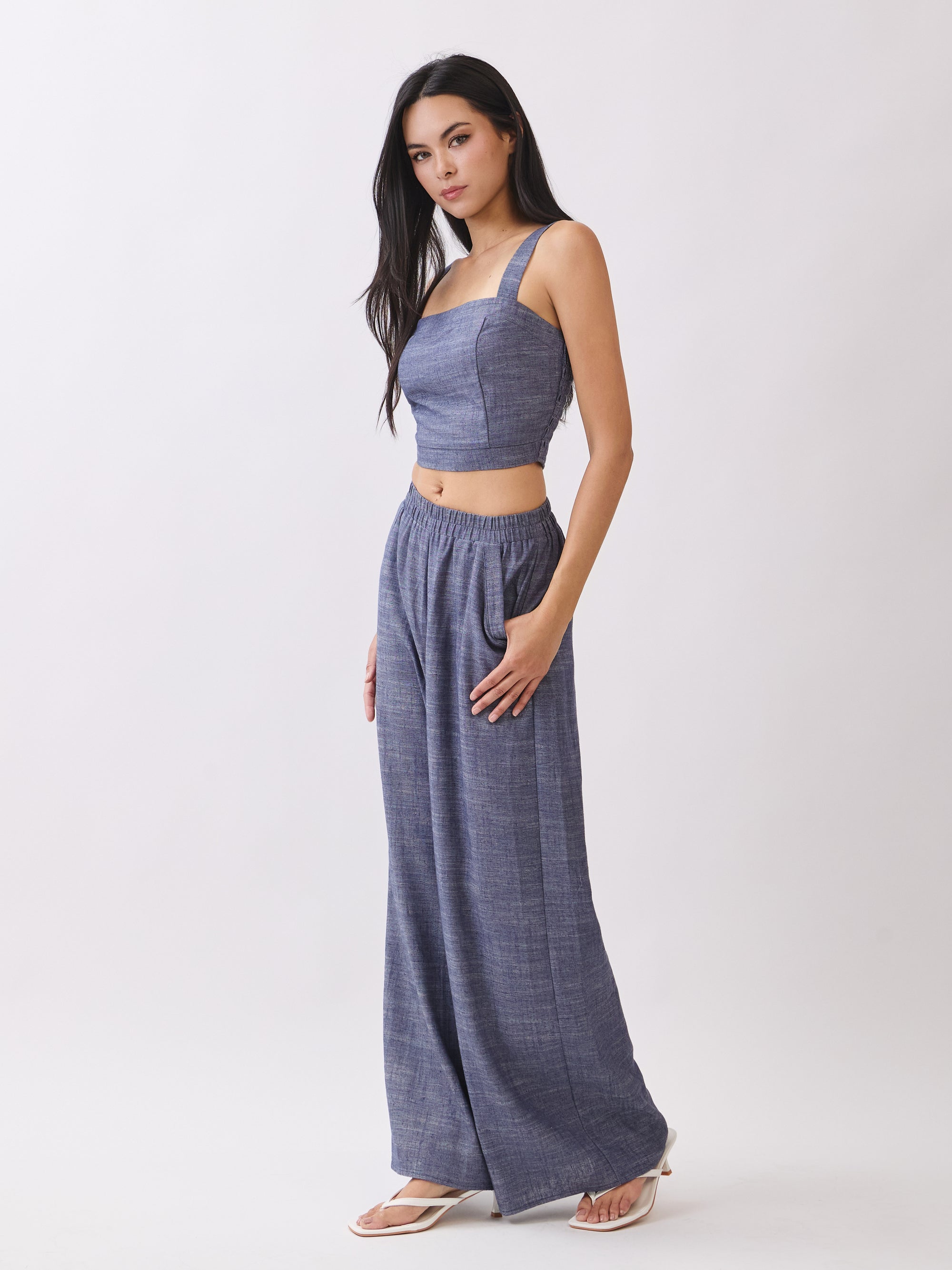 Side view of model wearing BTTRMMT Denim Olivyn Set in blue, featuring a square-neck cropped top and matching high-waist wide-leg pants.
