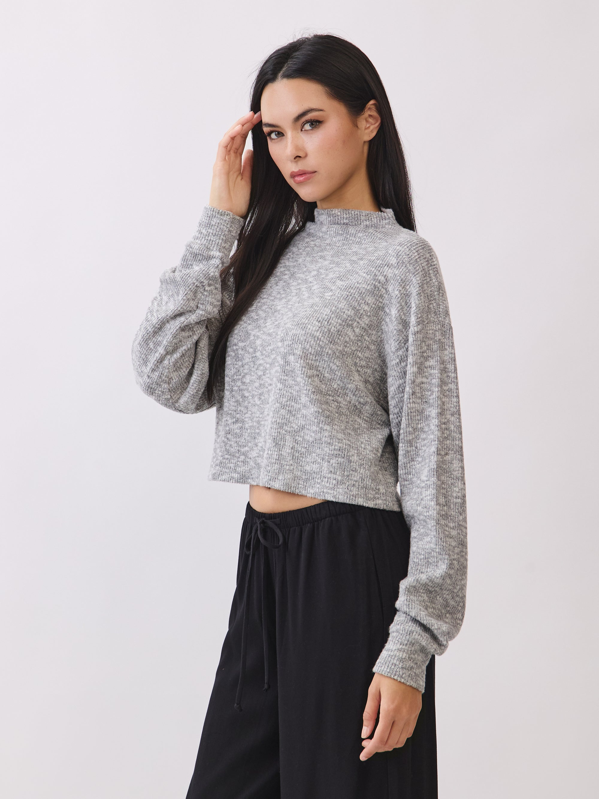 Side view of model wearing the BTTRMMT Elina High Neck Sweater in gray, a soft cropped knit with long sleeves.